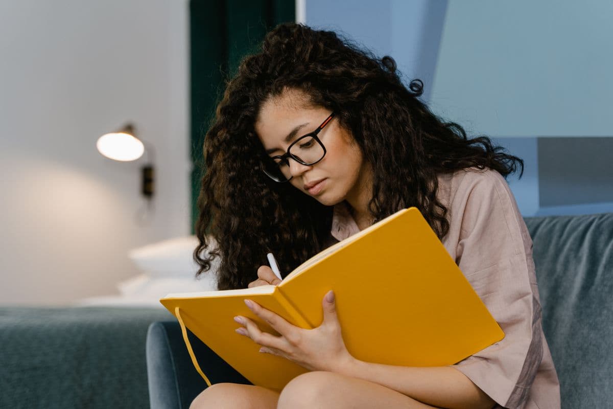 A woman writing her goals in a journal by warm lamplight